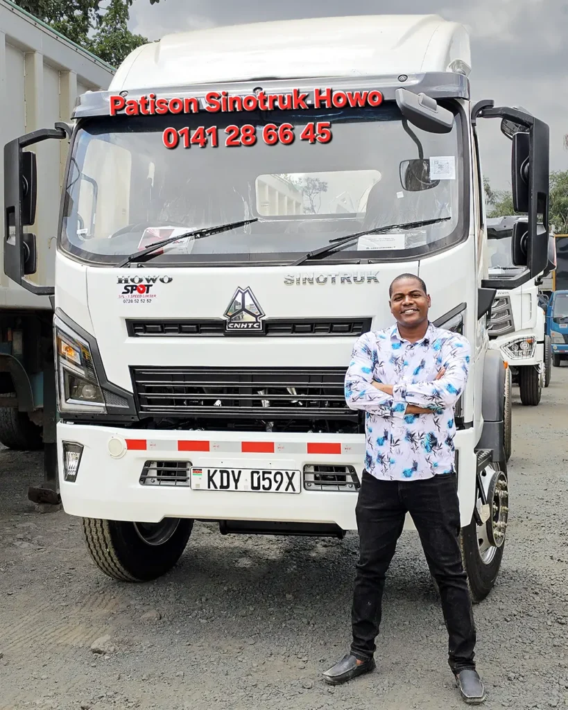 A man in a patterned shirt stands with arms folded in front of a new white Sinotruk Howo M3 Rigid 5200MM, registration KDY 059X, one of three trucks delivered to Shechem Events