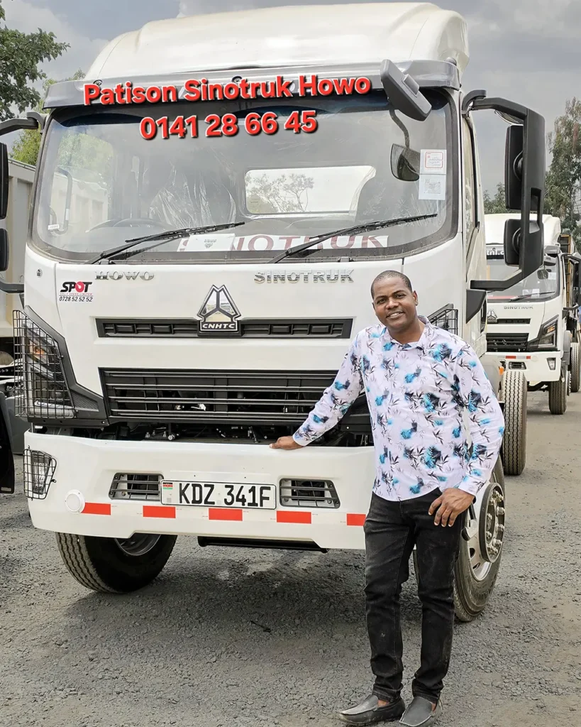 A man in a patterned shirt rests a hand on the bumper of a new white Sinotruk Howo M3 Rigid 5200MM with headlamp guards, registration KDZ 341F, one of three trucks delivered to Shechem Events